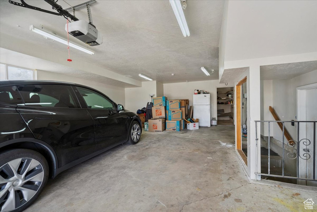 Garage featuring freestanding refrigerator and a garage door opener