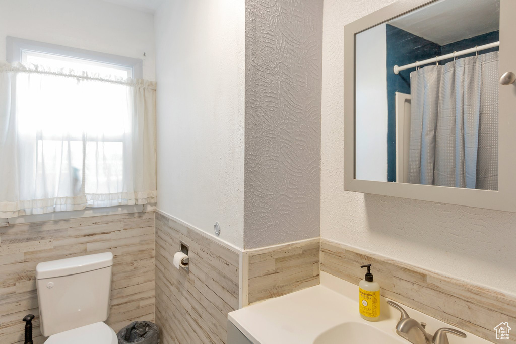 Full bath with vanity, wainscoting, a textured wall, and tile walls