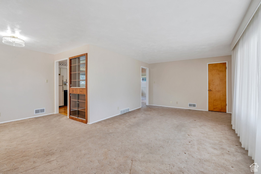 Unfurnished room featuring light carpet and baseboards