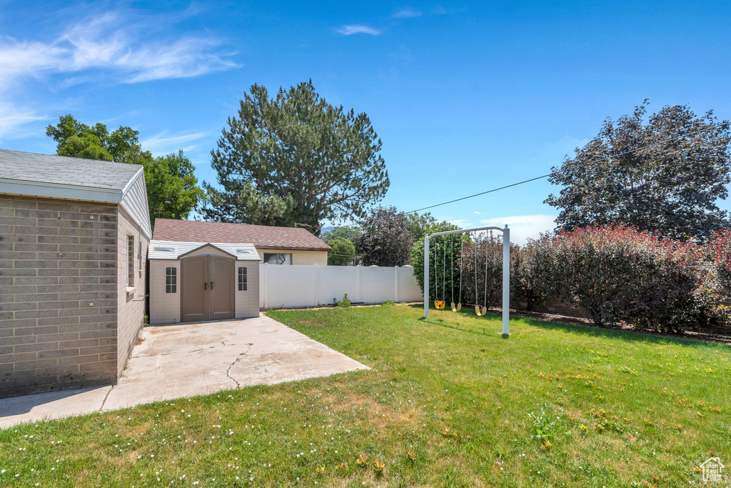 Fenced backyard with a storage unit and a patio