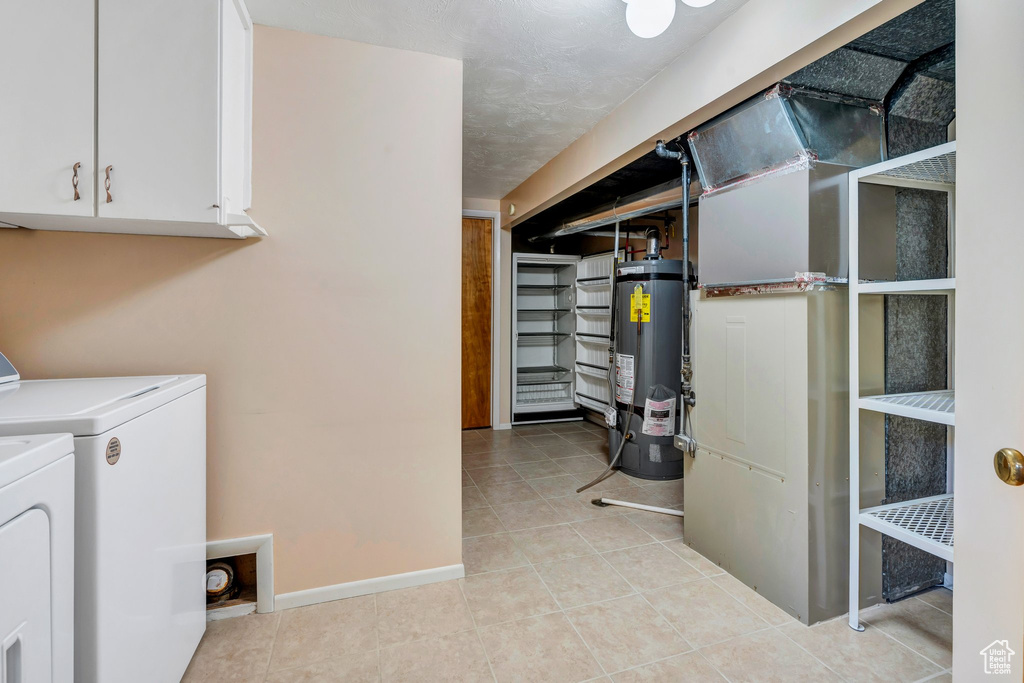 Below grade area featuring secured water heater, washing machine and clothes dryer, and light tile patterned flooring