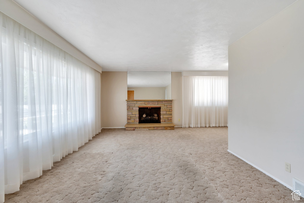 Unfurnished living room featuring carpet floors and a fireplace