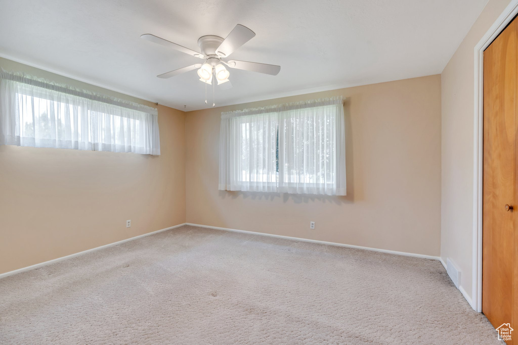 Carpeted empty room featuring baseboards and a ceiling fan