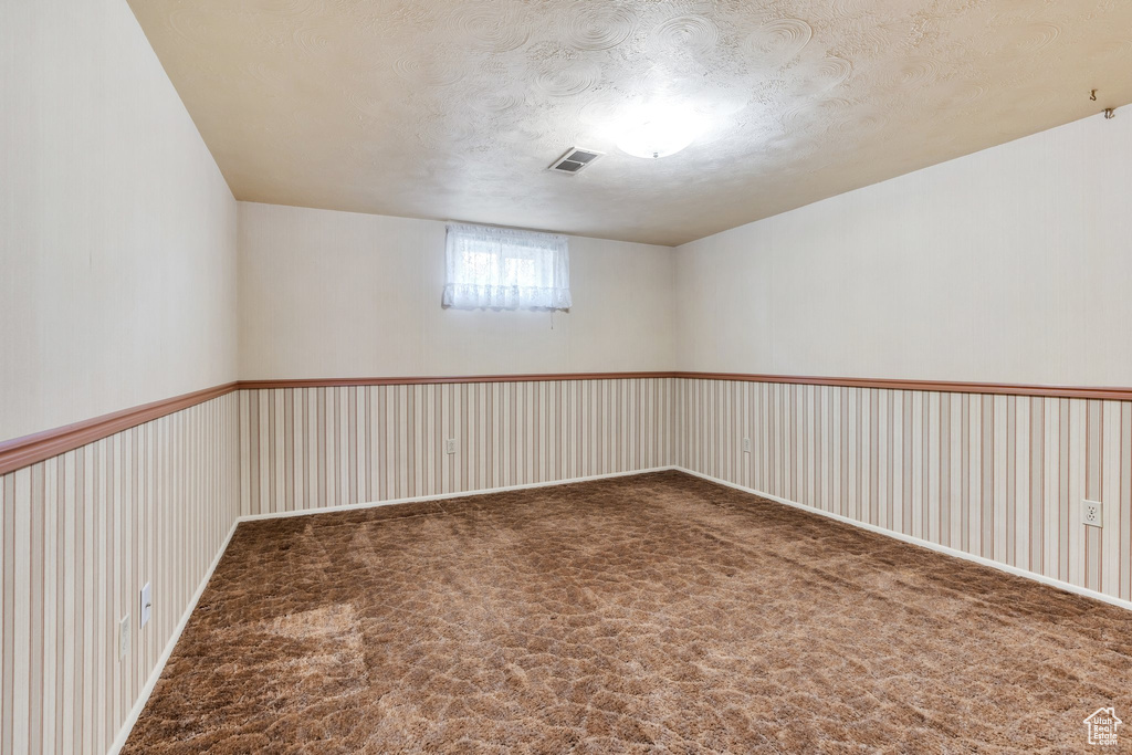 Empty room with carpet floors and a textured ceiling