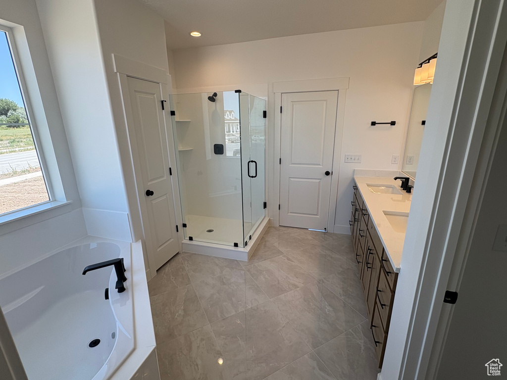 Bathroom featuring a shower stall, a garden tub, and double vanity