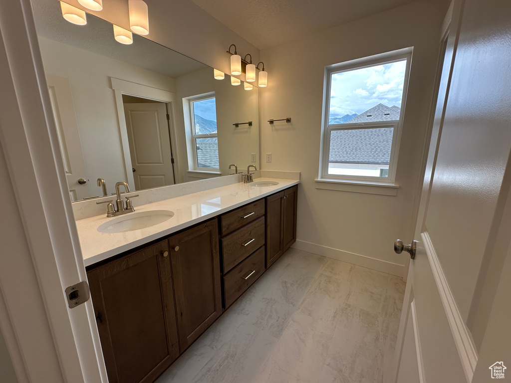 Full bathroom featuring double vanity and marble look tile flooring