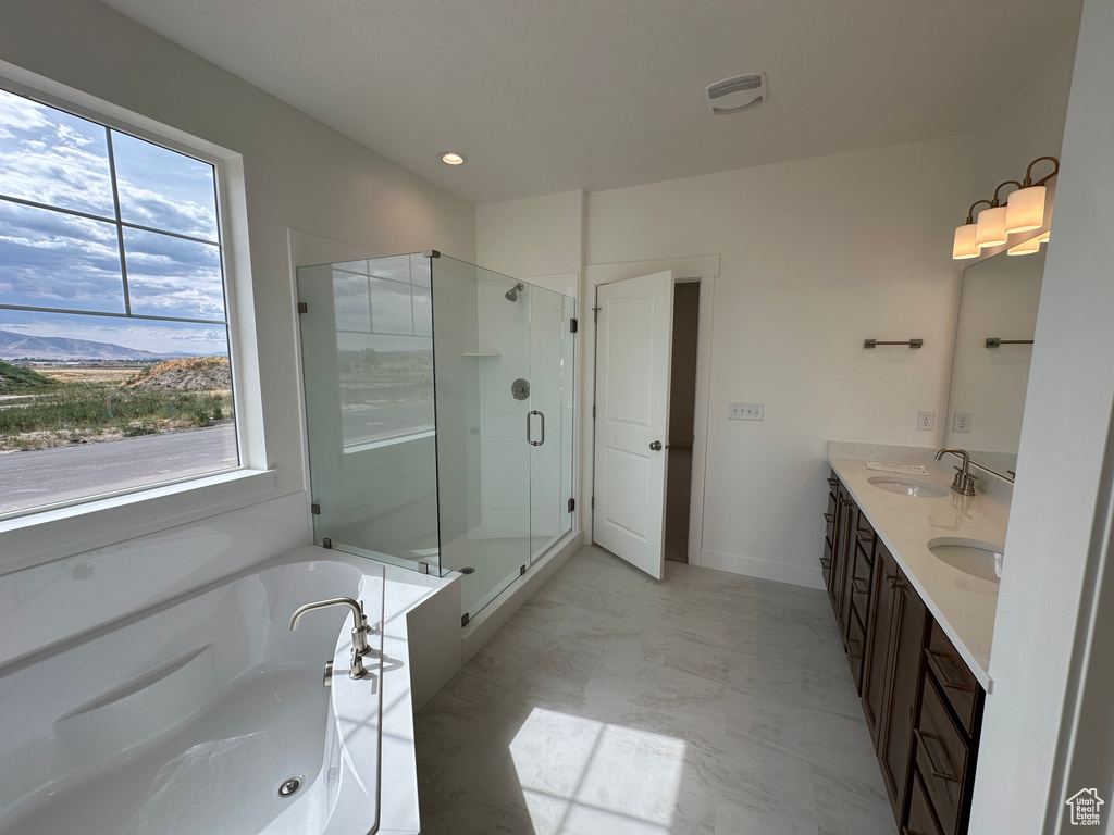 Bathroom with healthy amount of natural light, double vanity, a shower stall, and a whirlpool tub