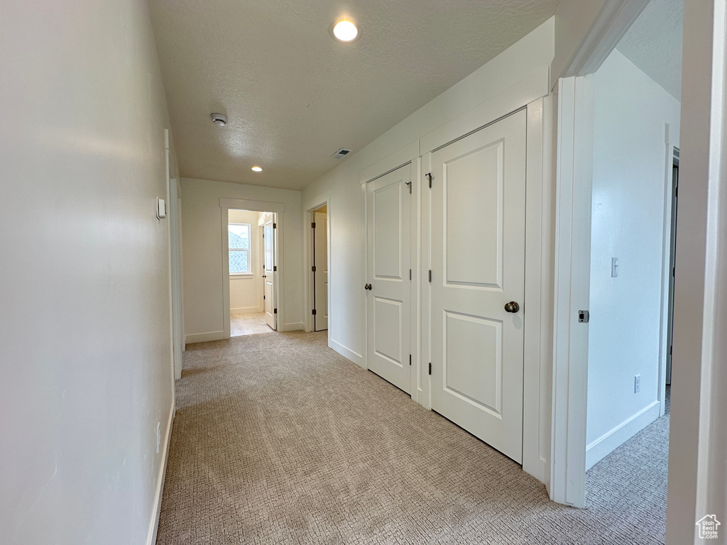 Hall with light carpet, recessed lighting, and a textured ceiling