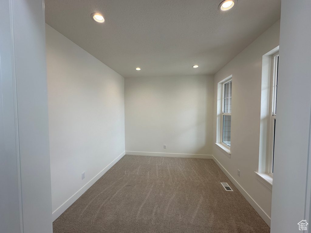 Carpeted empty room featuring recessed lighting