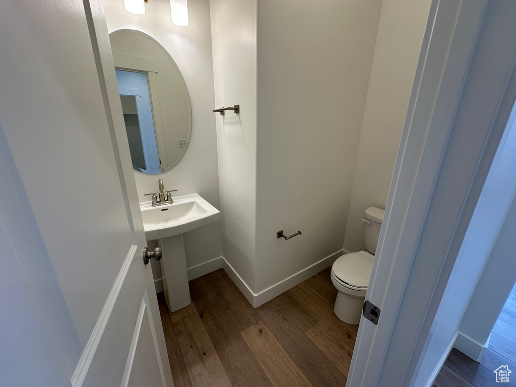 Half bath featuring wood finished floors and toilet
