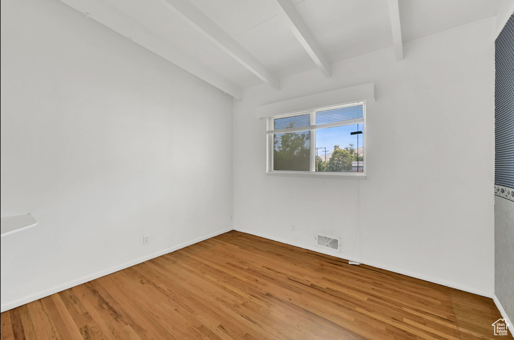Unfurnished room featuring beamed ceiling and light wood-style floors