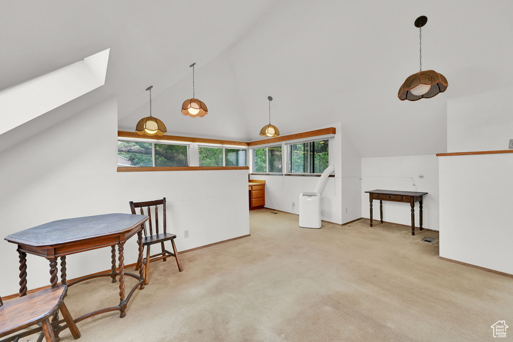 Sitting room featuring healthy amount of natural light, a skylight, light carpet, and high vaulted ceiling