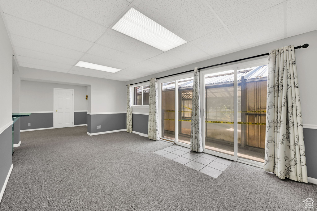 Carpeted empty room featuring a drop ceiling and baseboards