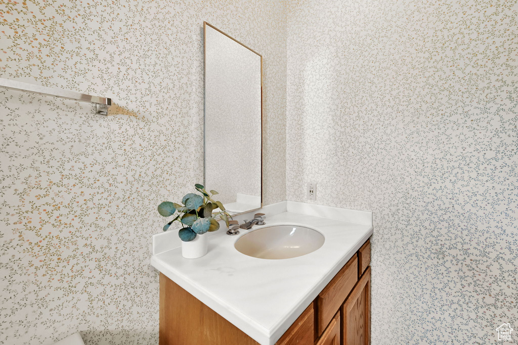 Bathroom with wallpapered walls and vanity