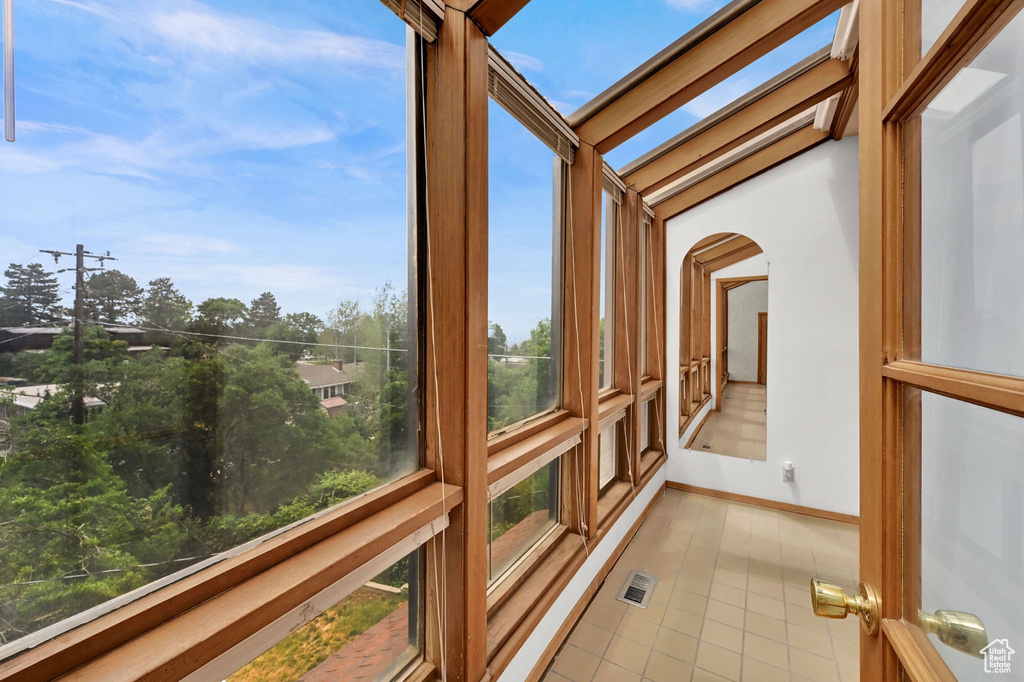 Unfurnished sunroom with tile patterned floors and arched walkways