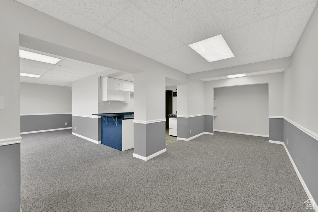 Finished basement with a paneled ceiling and carpet floors