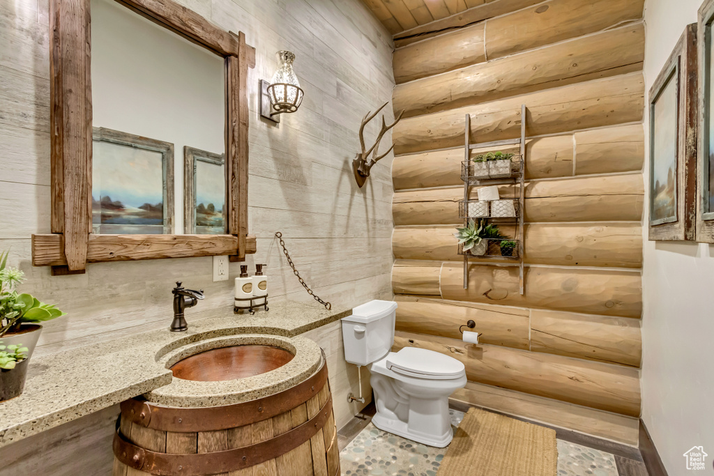 Half bath featuring rustic walls, vanity, and wooden ceiling