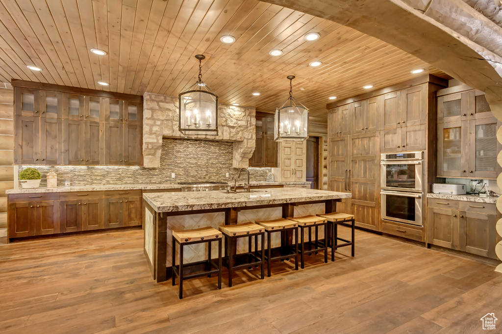 Kitchen with stainless steel appliances, wood ceiling, recessed lighting, an island with sink, and a chandelier