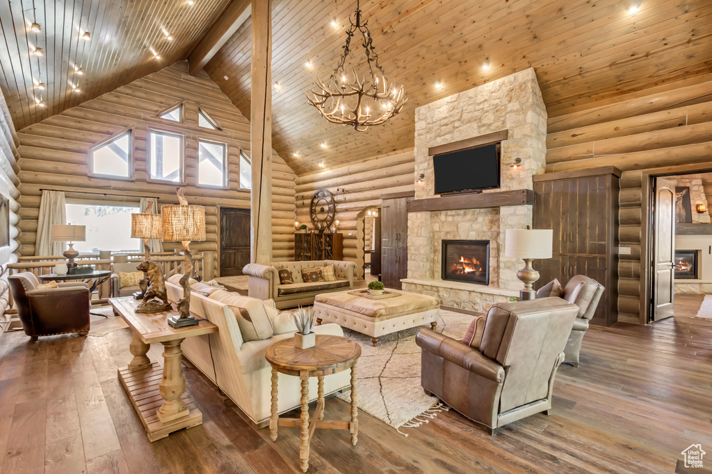 Living room featuring high vaulted ceiling, rustic walls, a stone fireplace, hardwood / wood-style floors, and a wood ceiling with exposed beams