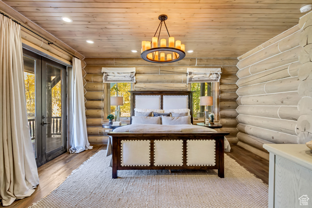 Bedroom with log walls, hardwood / wood-style flooring, multiple windows, access to exterior, and wooden ceiling