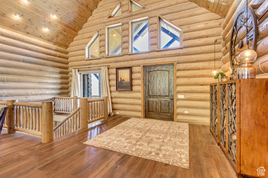 Entrance foyer featuring rustic walls, wood ceiling, hardwood / wood-style flooring, high vaulted ceiling, and plenty of natural light