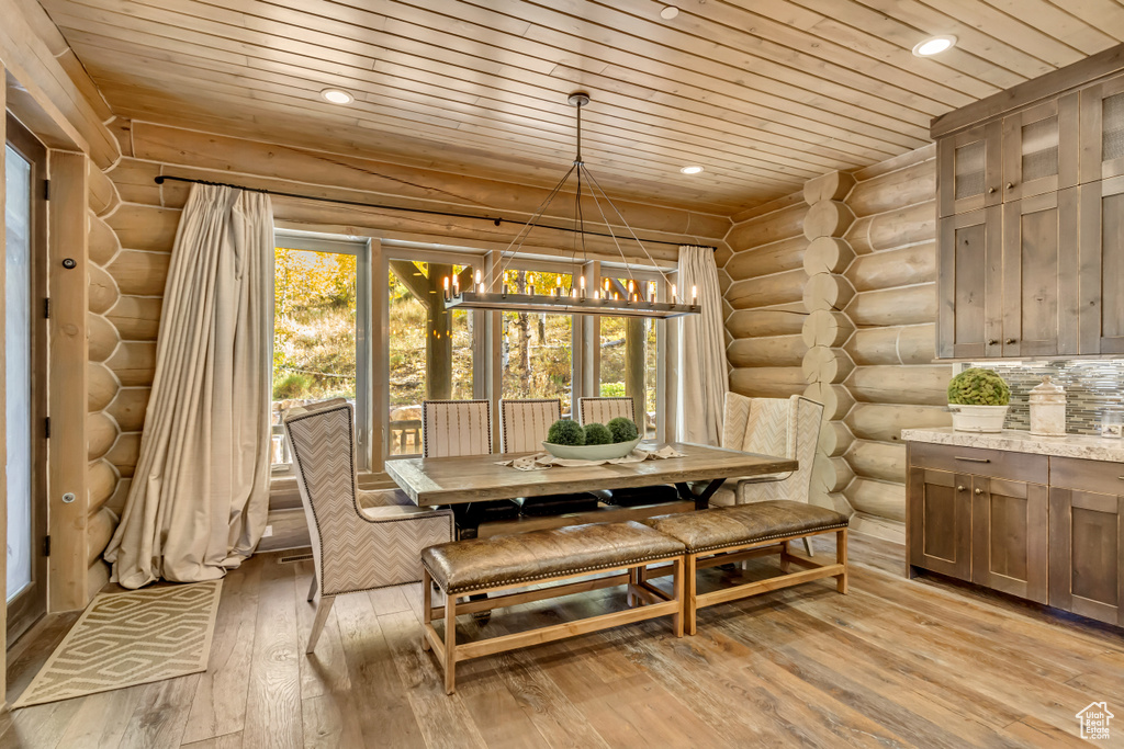 Dining area with wooden ceiling, rustic walls, a chandelier, light wood-style flooring, and recessed lighting