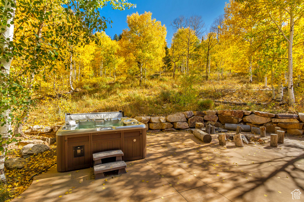 View of patio featuring a hot tub and a view of trees