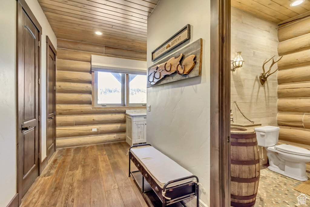Hallway with wood ceiling, rustic walls, and hardwood / wood-style floors