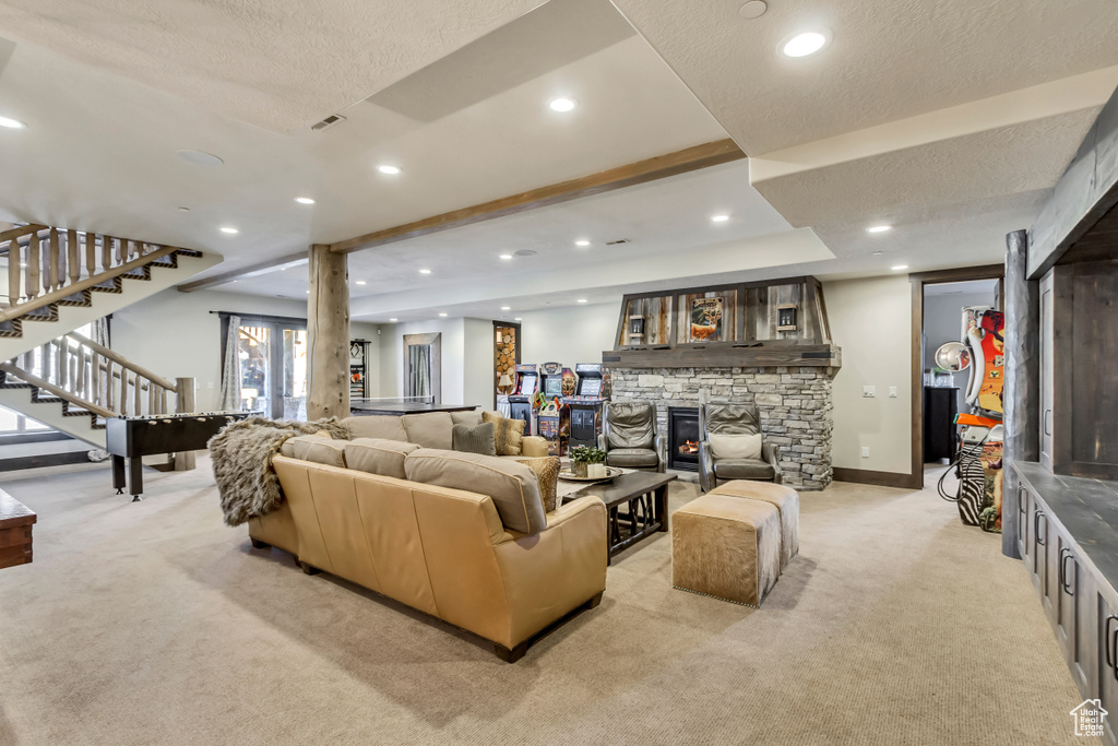 Living room featuring light carpet, stairway, recessed lighting, a textured ceiling, and a stone fireplace