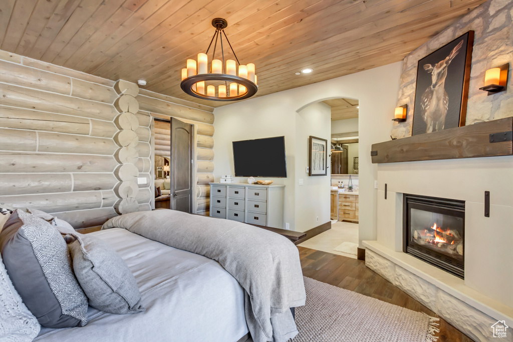 Bedroom with log walls, wood ceiling, wood-type flooring, arched walkways, and recessed lighting