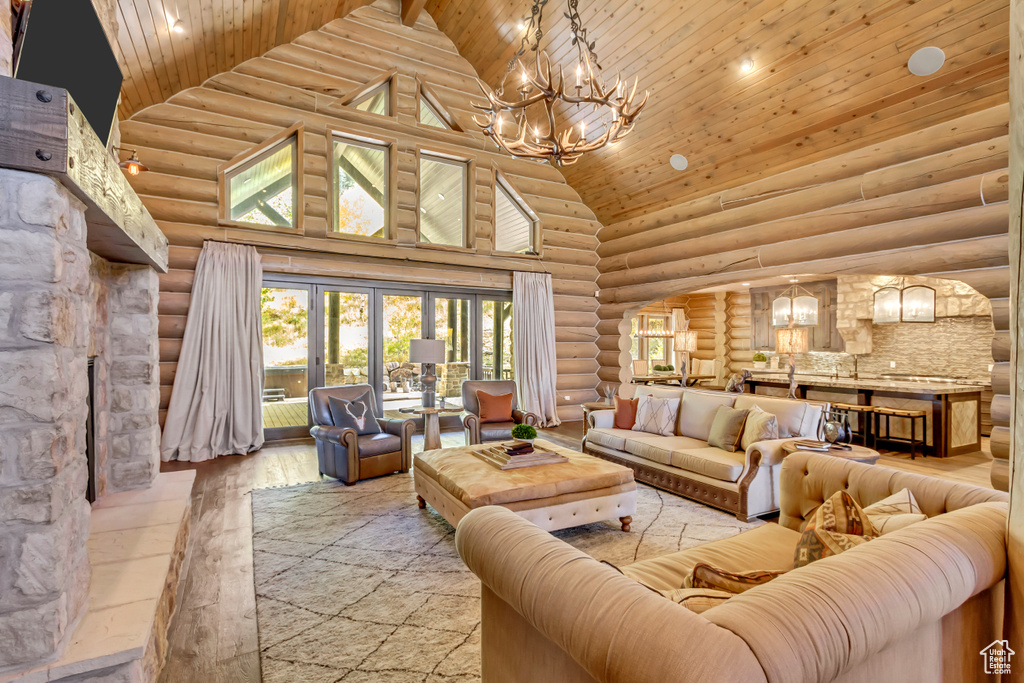 Living room with high vaulted ceiling, wood ceiling, a chandelier, log walls, and hardwood / wood-style floors