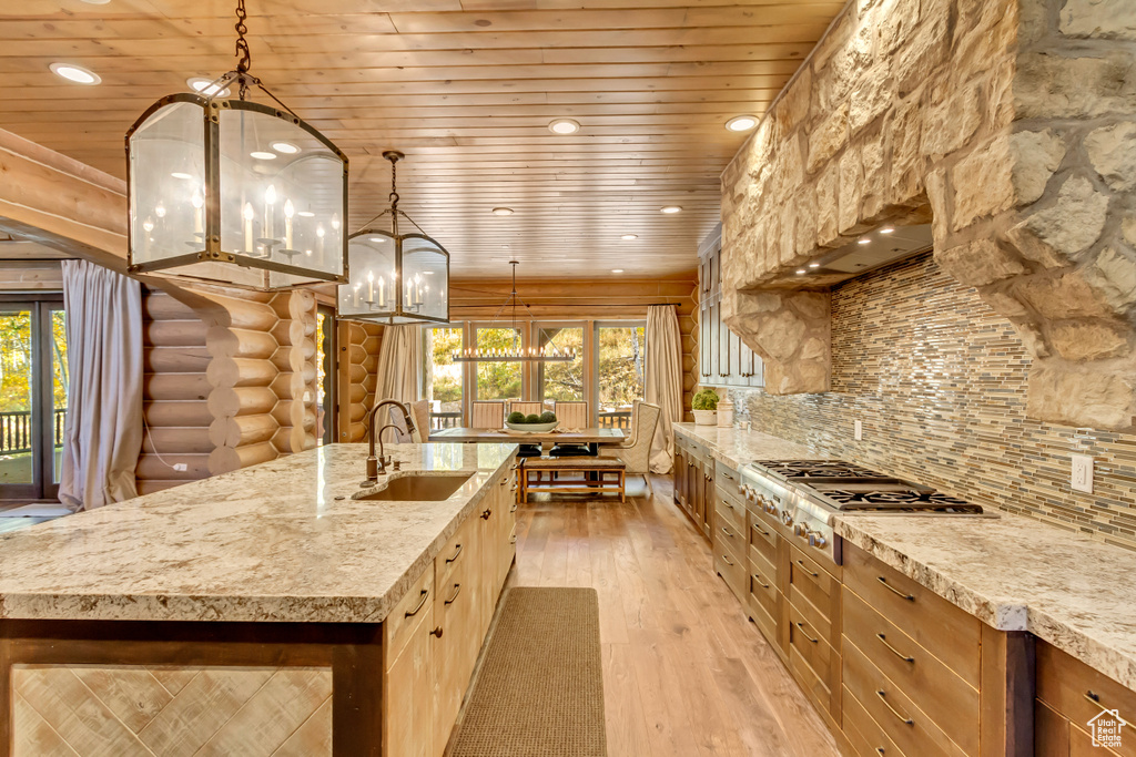 Kitchen featuring stainless steel gas stovetop, a chandelier, rustic walls, wooden ceiling, and light wood finished floors