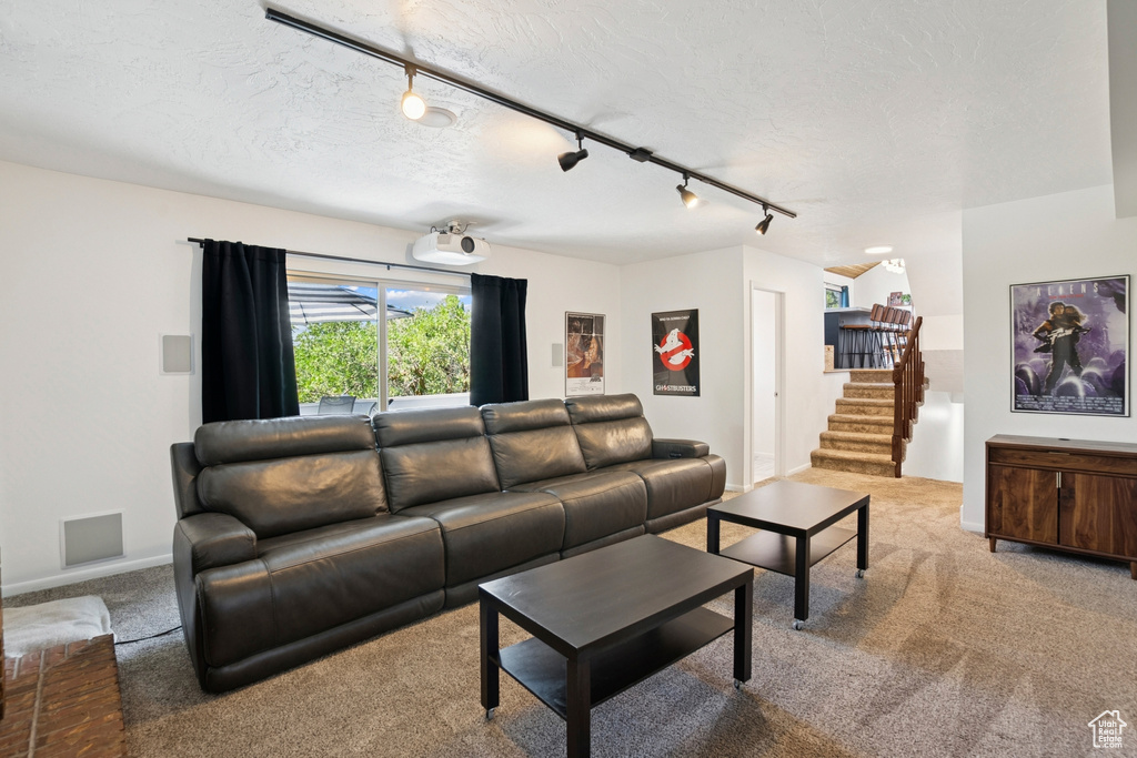 Carpeted living area featuring track lighting, stairs, and a textured ceiling
