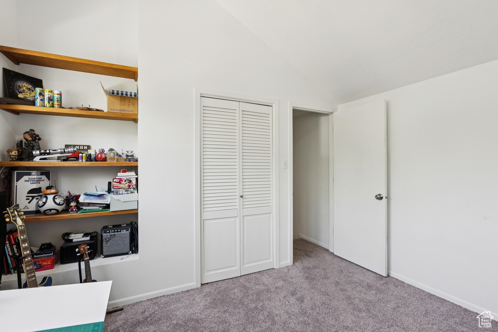Bedroom featuring carpet flooring, lofted ceiling, and a closet