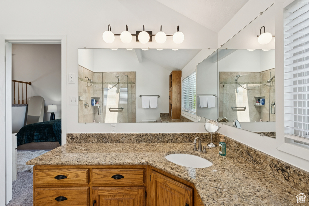 Ensuite bathroom featuring lofted ceiling, a shower stall, and vanity