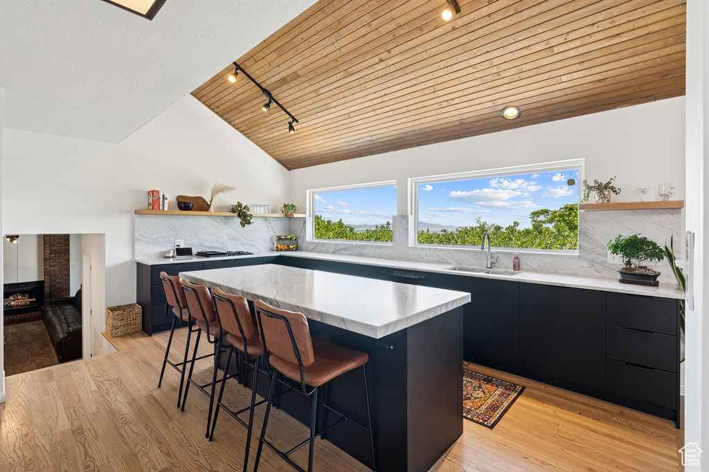 Kitchen featuring open shelves, a breakfast bar area, dark cabinetry, track lighting, and wood ceiling