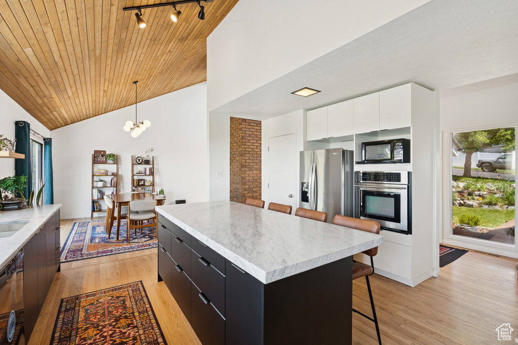 Kitchen with black appliances, modern cabinets, dark cabinets, a breakfast bar area, and light wood-style floors