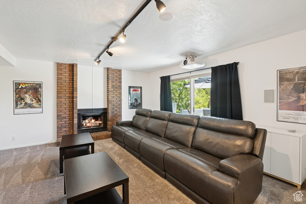 Carpeted living area with a textured ceiling, a brick fireplace, and track lighting