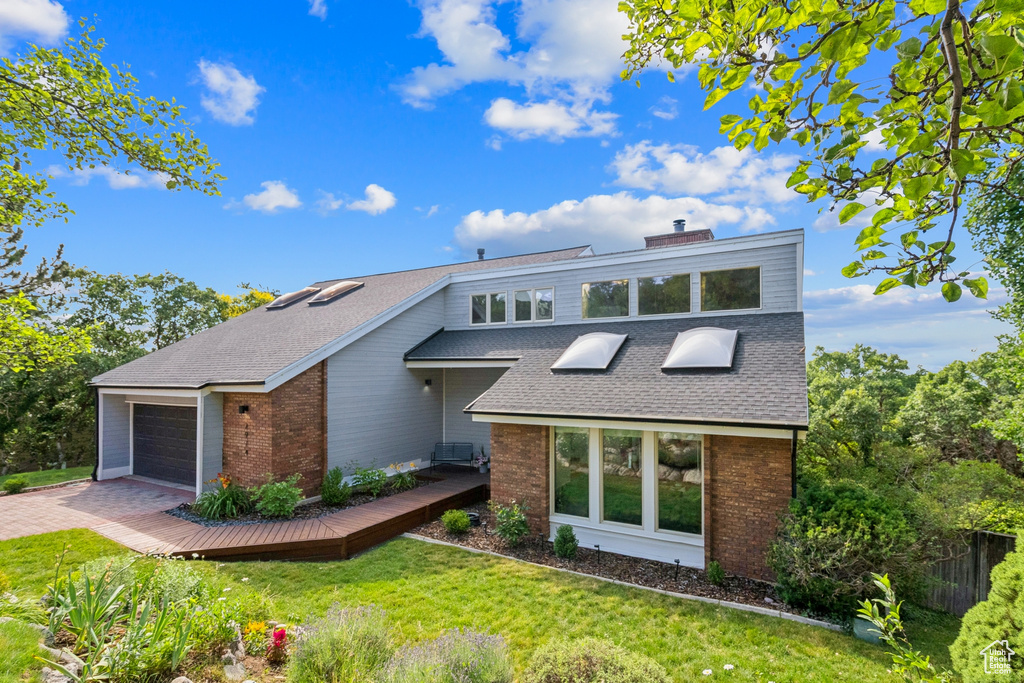 View of front of house featuring brick siding, a front lawn, and roof with shingles