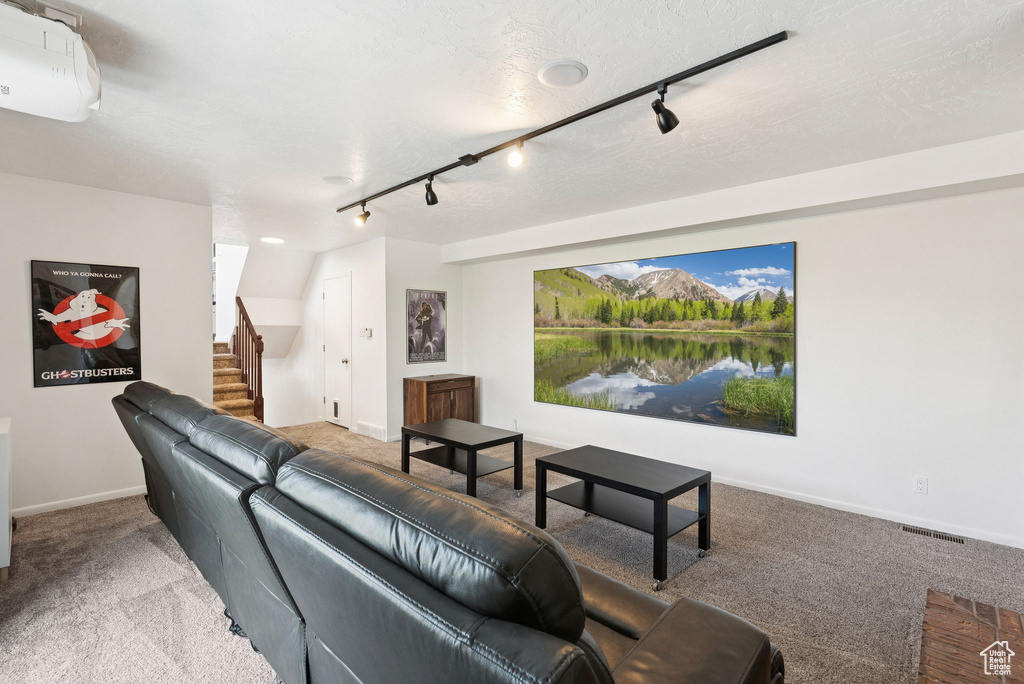 Carpeted living room featuring rail lighting and stairway