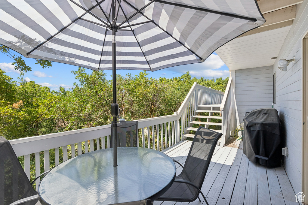 Wooden terrace featuring outdoor dining area, grilling area, and stairway