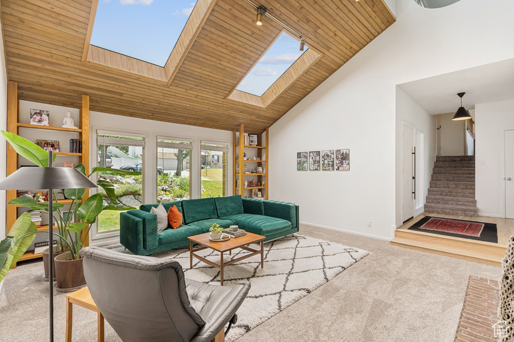 Carpeted living area featuring a skylight, wooden ceiling, high vaulted ceiling, and stairs