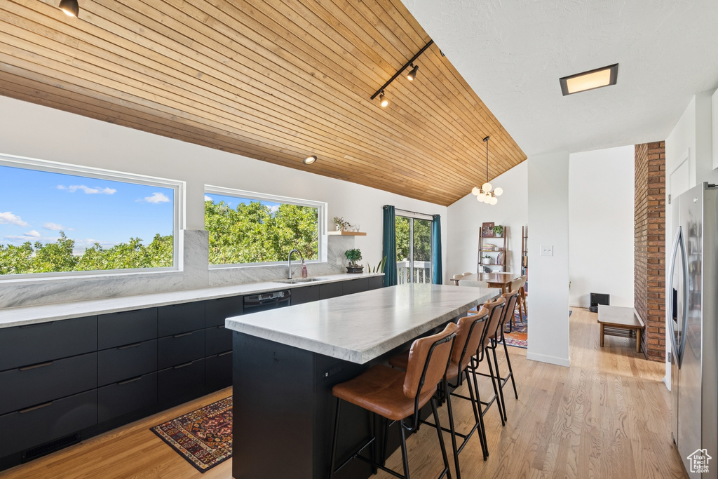 Kitchen with freestanding refrigerator, wooden ceiling, a center island, a breakfast bar area, and modern cabinets