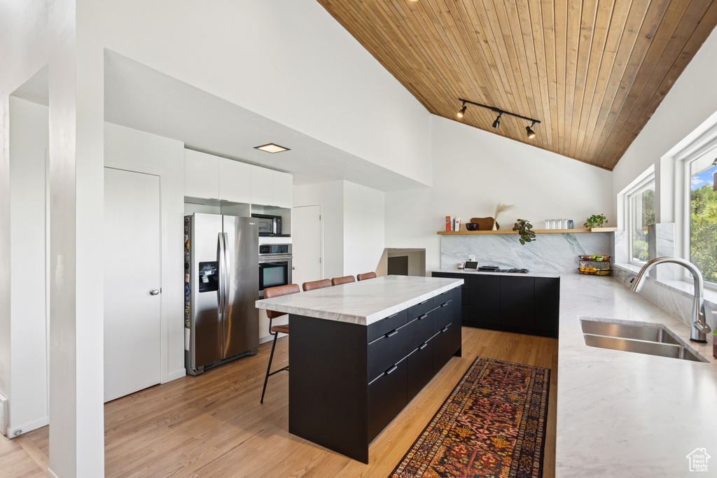 Kitchen featuring stainless steel appliances, dark cabinets, modern cabinets, wooden ceiling, and light countertops