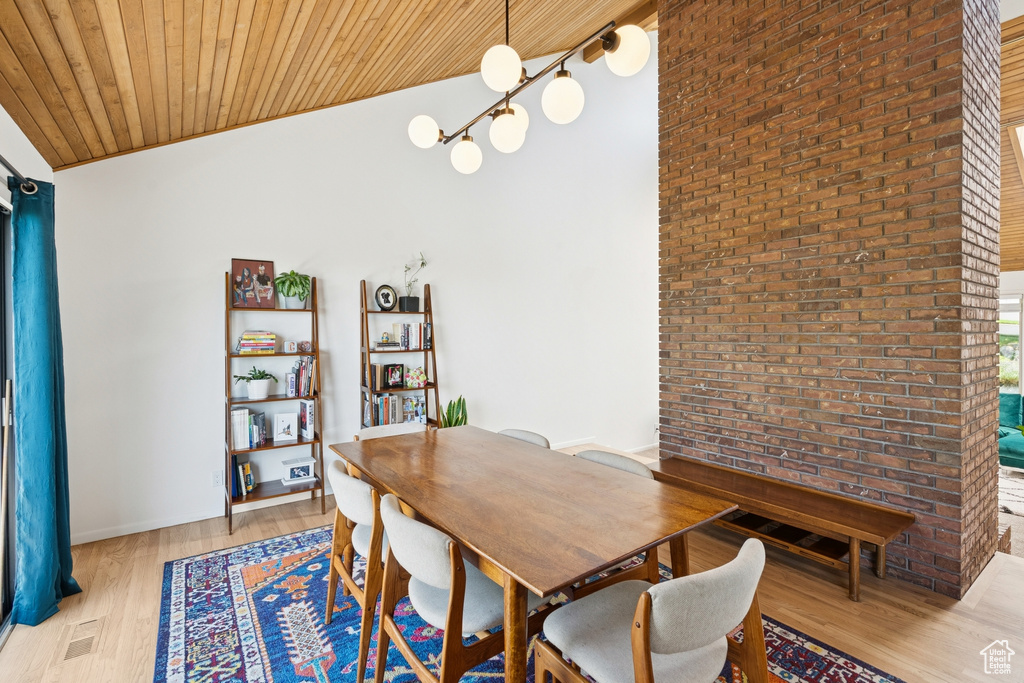Dining area with light wood-type flooring, wooden ceiling, and brick wall