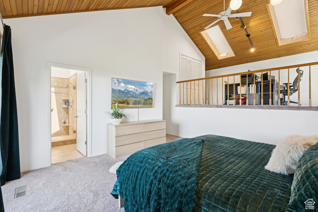 Carpeted bedroom with a skylight, wooden ceiling, high vaulted ceiling, and connected bathroom