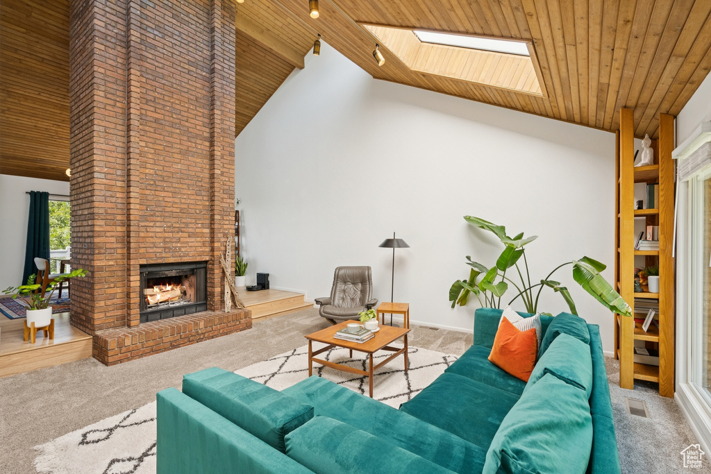 Carpeted living area featuring wooden ceiling, high vaulted ceiling, an outdoor brick fireplace, and a skylight