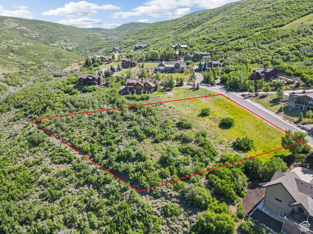 Aerial view of residential area featuring property boundaries highlighted and a mountainous background