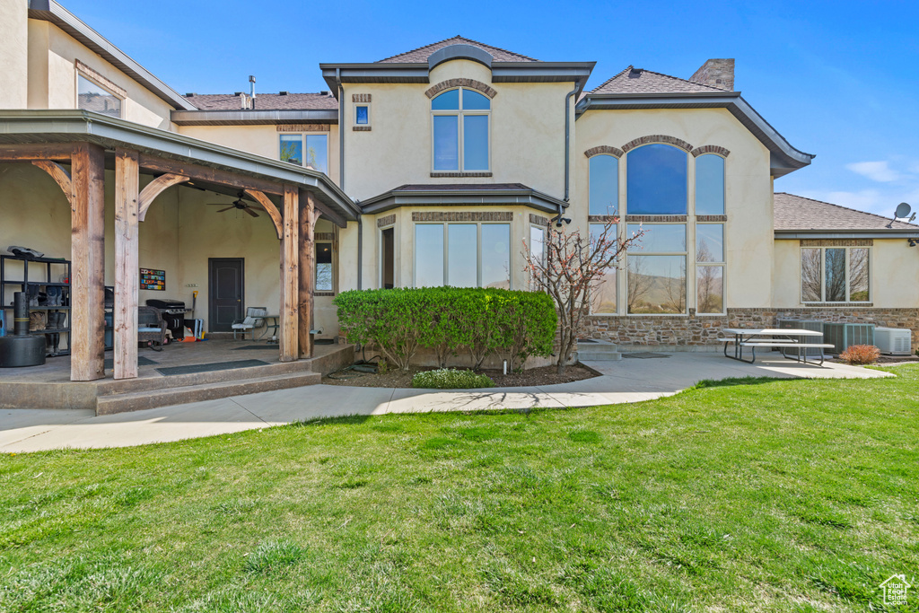 Back of house featuring stucco siding, a yard, ceiling fan, and a patio