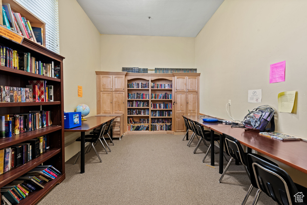 Office area featuring light colored carpet and wall of books